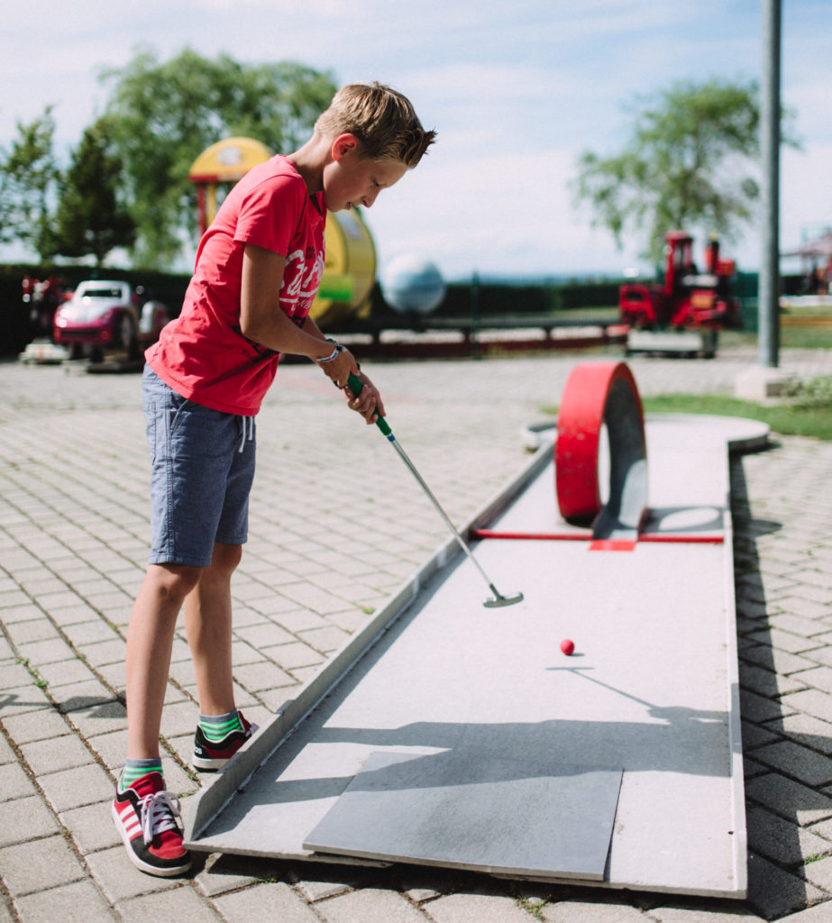 Kind spielt Minigolf